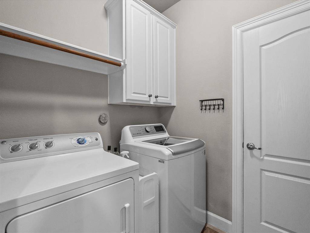 Convenient laundry room with built-in shelving, overhead storage, and space for a washer and dryer. This functional space adds practicality to the home, making laundry tasks more manageable
