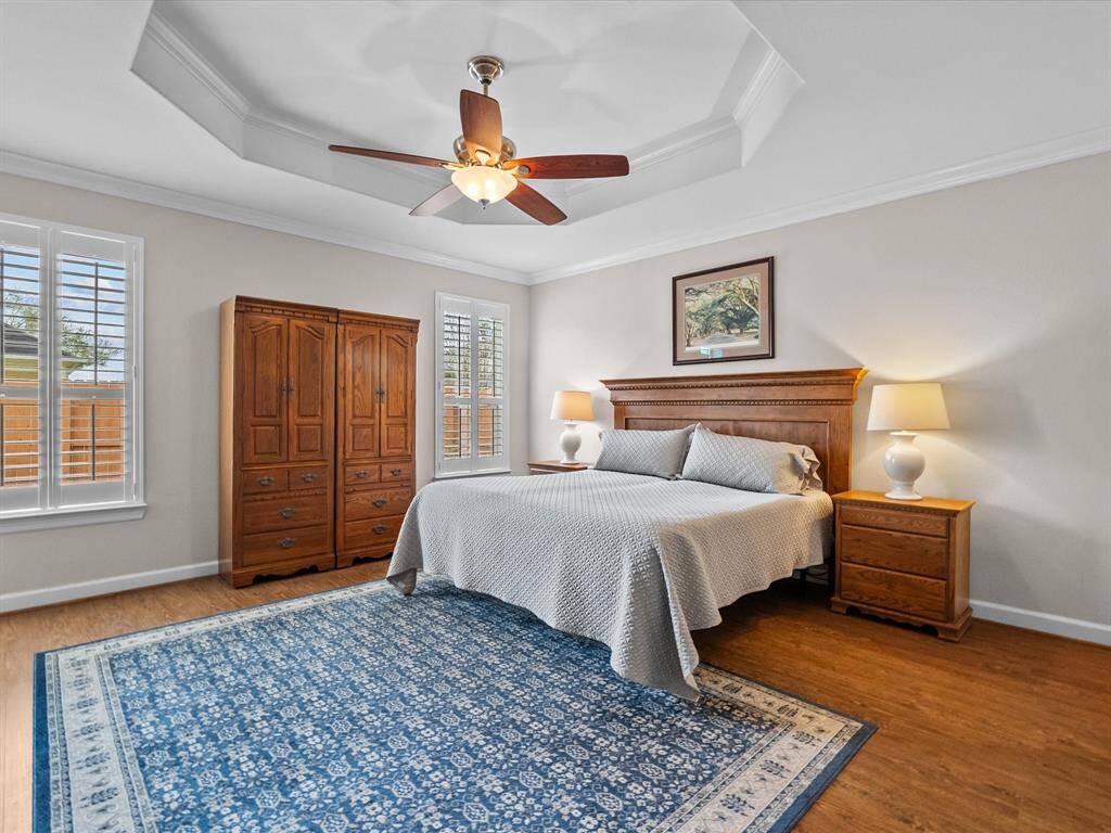 Massive primary suite with LVP flooring, featuring a tray ceiling and ample natural light
