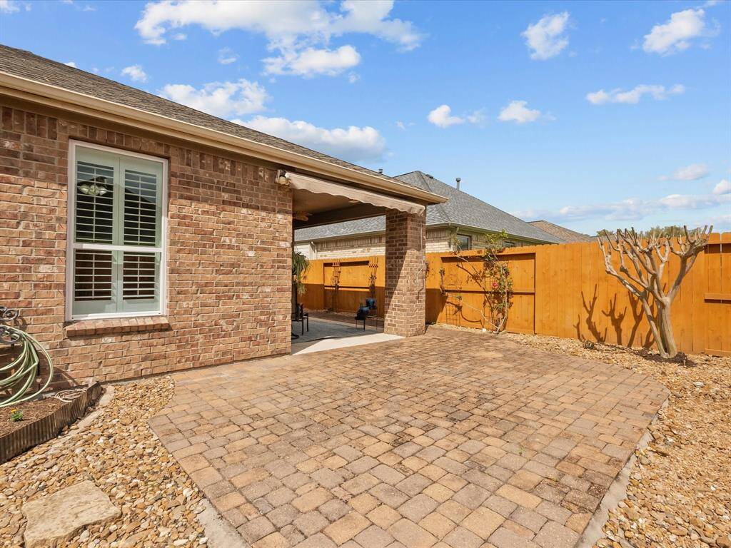 The covered patio has extended electric awning for extra shade on cobble stone extension offering a comfortable outdoor space for relaxation and entertaining. This backyard area features a privacy fence and low-maintenance landscaping.