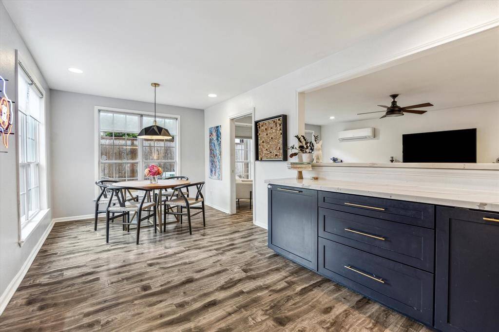 The kitchen is bright and open with large windows, modern lighting, and wood flooring.  It has an abundance of counter space and storage.