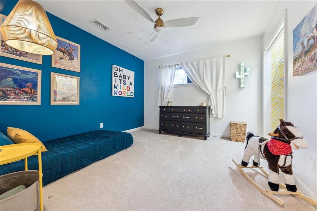 Another secondary bedroom features a ceiling fan and plush carpeting.