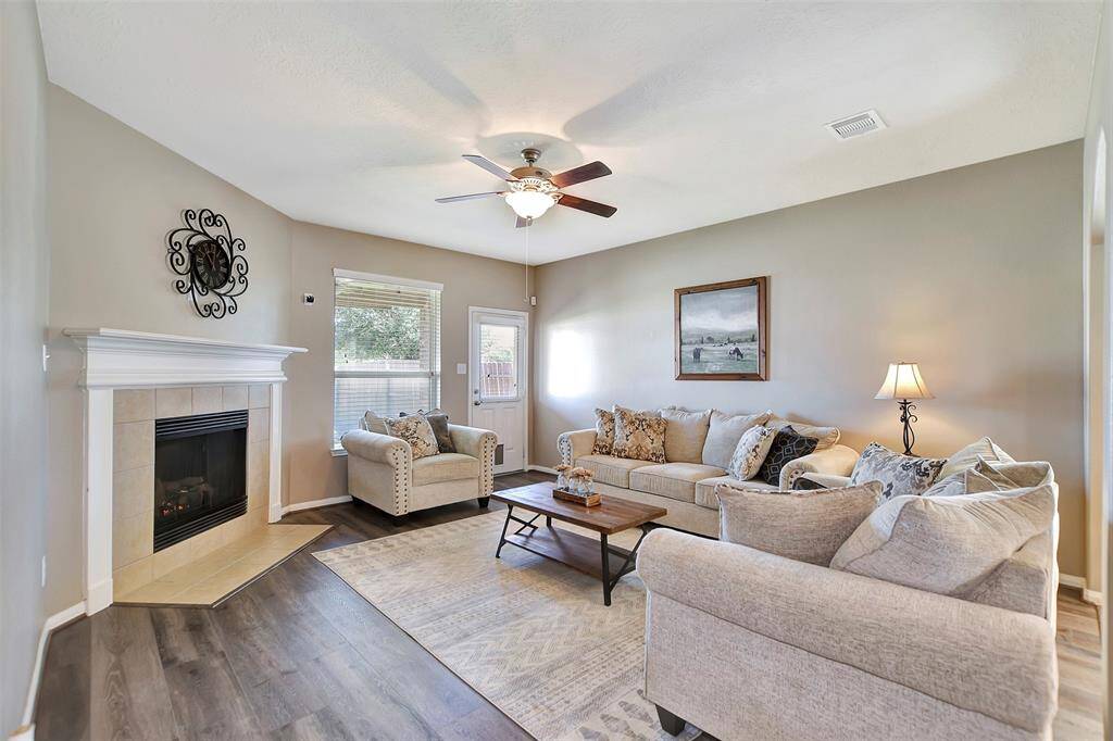 This cozy living room features neutral tones, a ceiling fan, and a fireplace.
