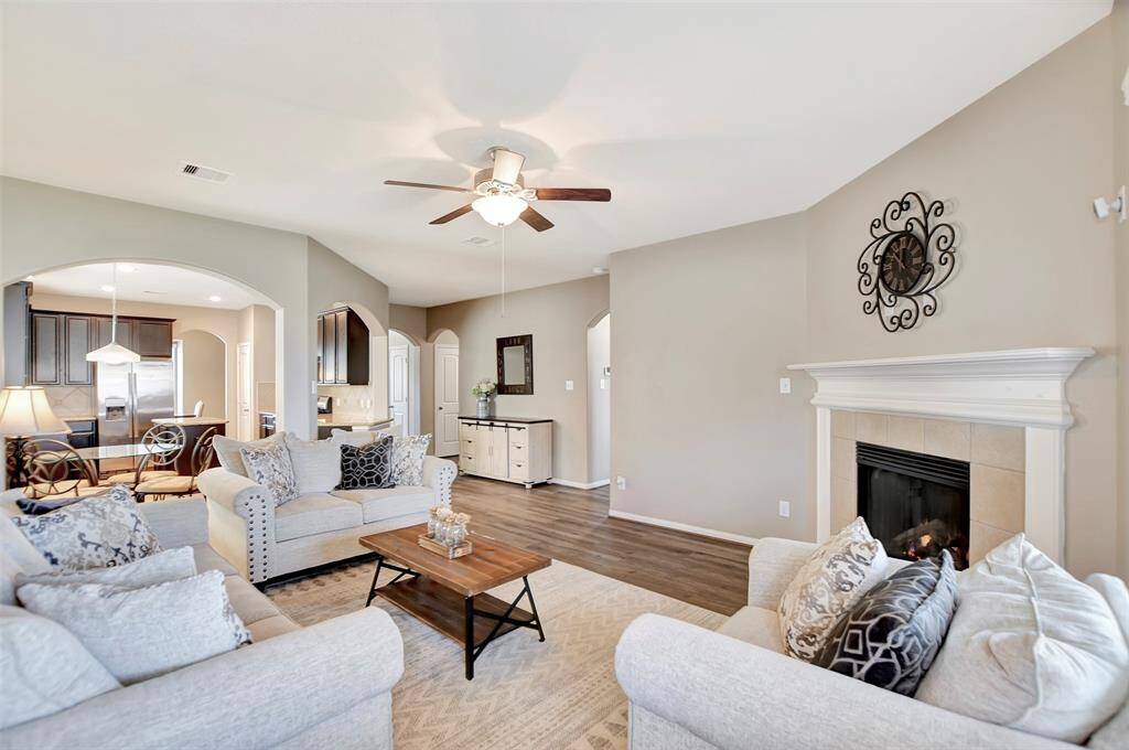 The living room opens to a modern kitchen with dark cabinetry and stainless steel appliances, creating a seamless flow for entertaining.