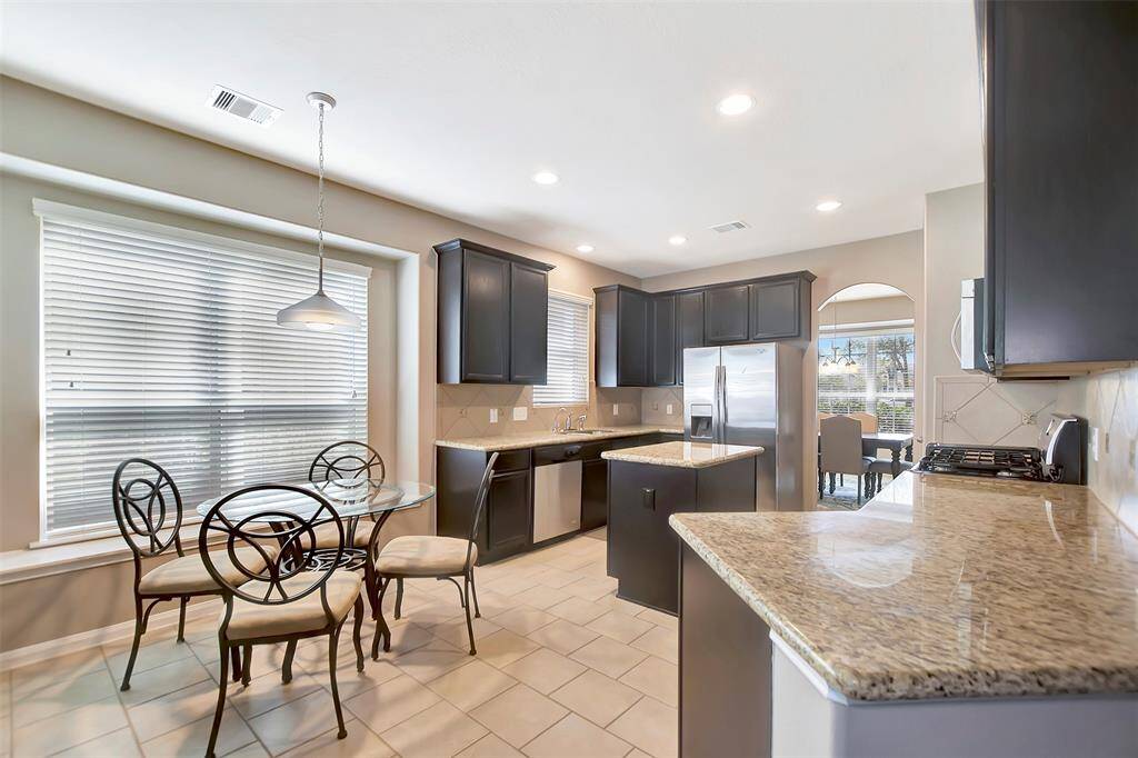 Modern kitchen with granite countertops, dark cabinetry, stainless steel appliances, and a central island.