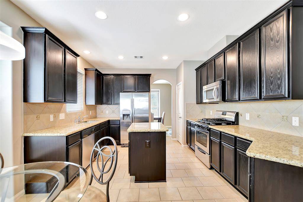 The kitchen includes a gas stove, an island, and natural light, creating a spacious and inviting cooking area.