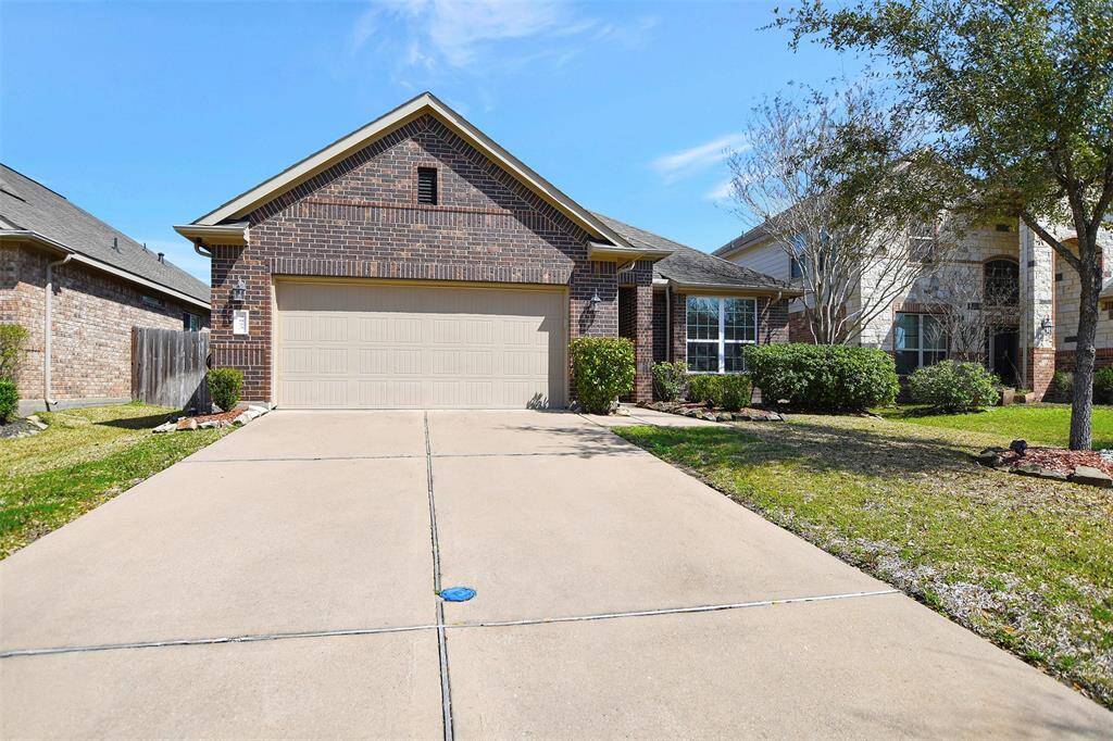 A charming single-story brick home with a two-car garage, well-maintained front lawn, and mature landscaping. The driveway is spacious, and the exterior features a mix of brick and siding, offering a welcoming curb appeal.