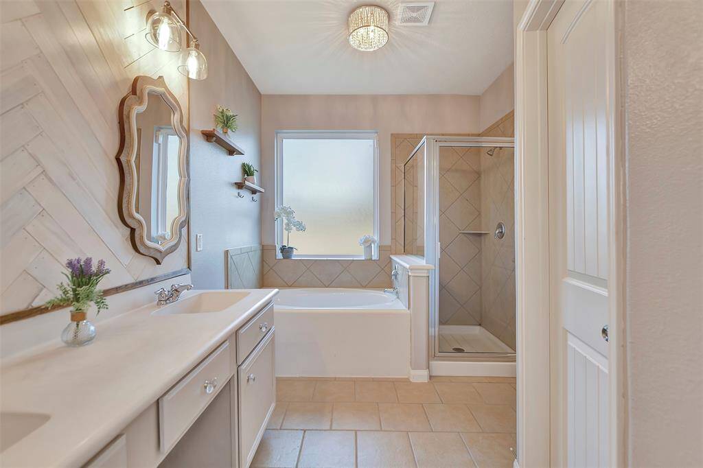 This bathroom features a sleek design with a large vanity and double sinks, 2 stylish mirrors, and elegant lighting.