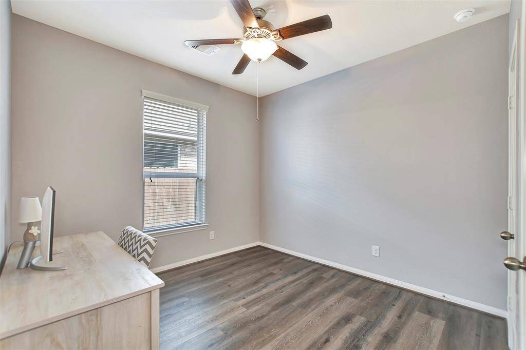 This room features neutral gray walls, a ceiling fan and window for natural light. It's ideal for a small office or study.