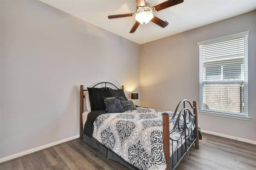 This cozy bedroom features neutral walls, a ceiling fan, and vinyl plank flooring.