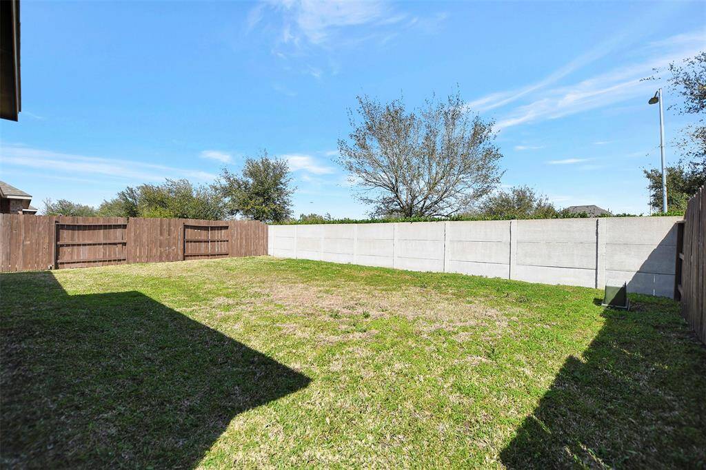 Spacious backyard enclosed by a wooden and concrete fence, offering privacy and potential for landscaping or outdoor activities.