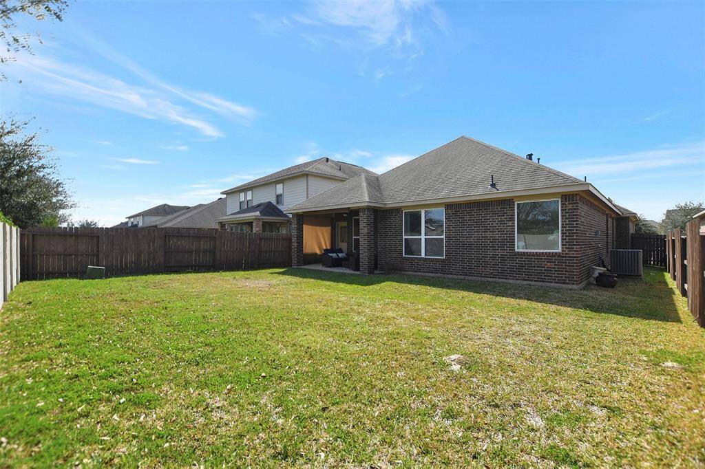 This photo shows a spacious backyard that is perfect for outdoor activities. The house features a brick exterior and large windows.