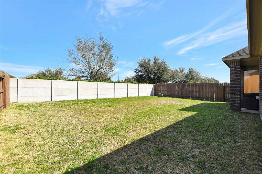 Spacious backyard with a mix of wooden and concrete fencing, offering privacy and ample lawn space. Ideal for outdoor activities and gardening.