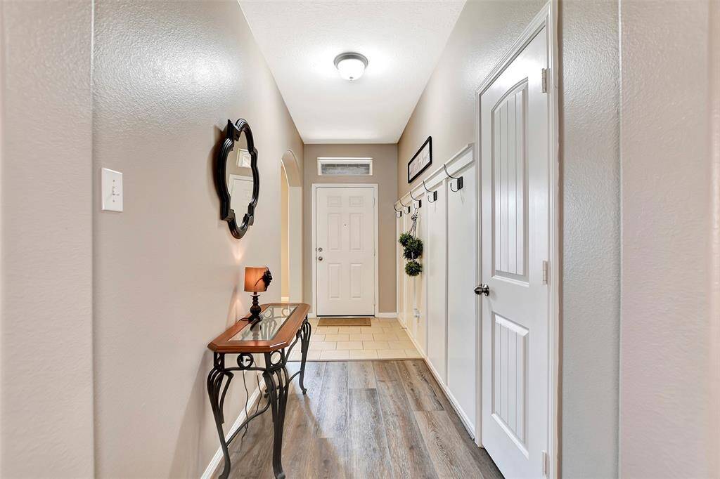 This welcoming entryway features a blend of tile and vinyl plank flooring & neutral walls. The hallway includes a decorative wall with coat hooks. Perfect for coat and/or backpacks.