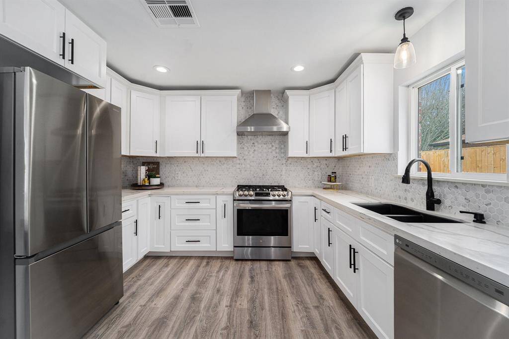 This kitchen features modern stainless steel appliances,white cabinetry, deep drawes and a stylish backsplash. Ideal for a functional cooking area.