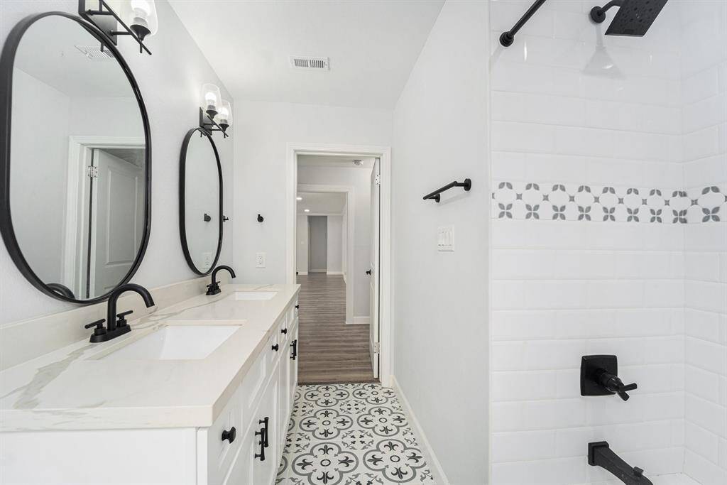 Stylish patterned floor tiles. The shower area includes a decorative tile accent and a sleek black showerhead.