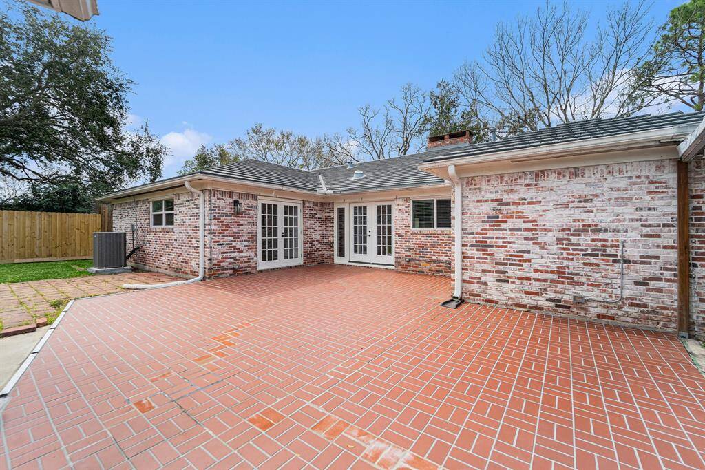 Spacious backyard patio with red brick flooring and a brick exterior.  The area is open and ideal for outdoor gatherings.