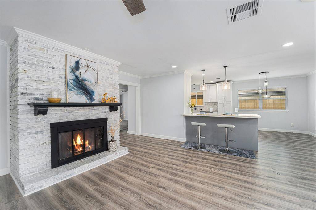 White brick fireplace in cozy family room and a spacious kitchen featuring a breakfast bar with stylish pendant lighting.