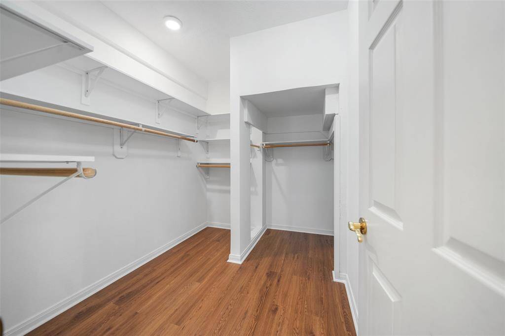 This spacious walk-in closet features warm wood flooring, providing plenty of storage and a clean, organized look.