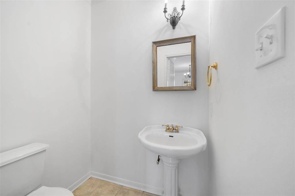 Sleek half bathroom featuring a contemporary pedestal sink and rustic framed mirror for added style.