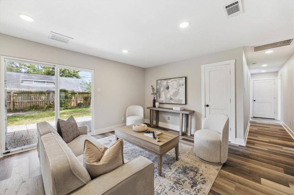 The family room provides a spacious and inviting setting for friends and family to relax and unwind, featuring LVP flooring, neutral paint, and abundant natural light. Sliding glass doors offer seamless indoor-outdoor living, leading directly to the backyard patio, perfect for entertaining or enjoying quiet morings in the fresh air.