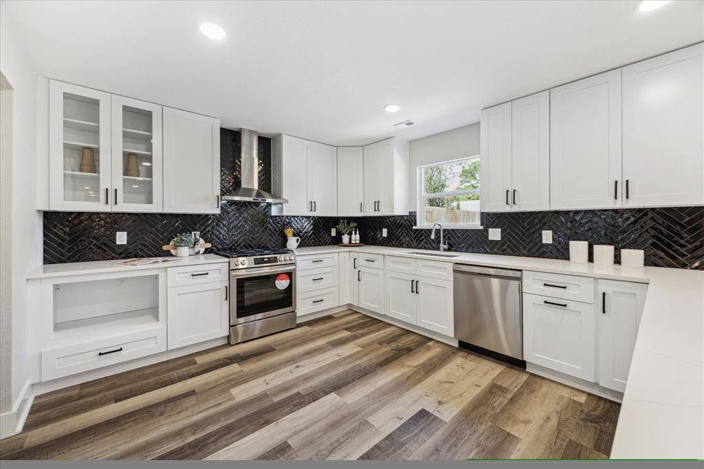 Ditch the takeout and cook from home more often! This fully loaded updated kitchen offers crisp white cabinetry with modern pulls, oversized drawers and some glass front uppers, Quartz countertops, stunning tile backsplash, sleek stainless steel appliances, and a large walk-in pantry.