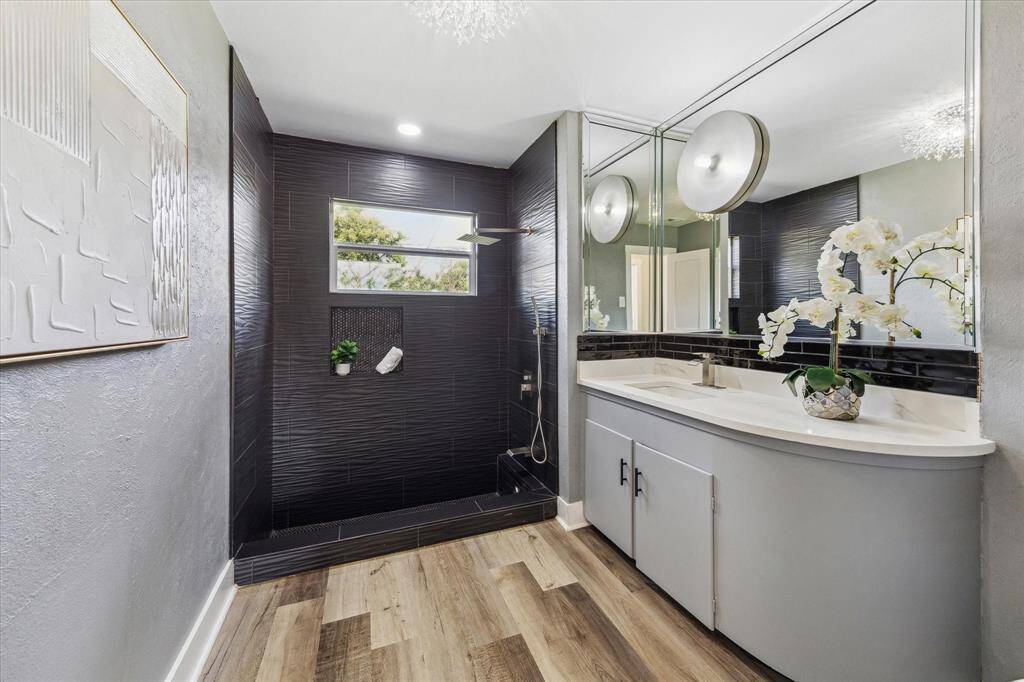 Beautifully updated with modern finishes, this full guest bathroom provides everything family and guests need to start their day in comfort. It features a fully tiled walk-in shower and an updated single sink vanity with ample storage below and a full mirror above, creating a space that is both functional and inviting.