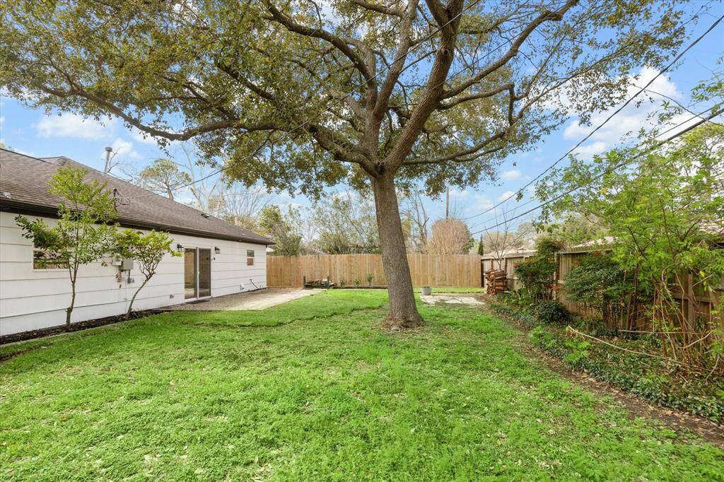 This expansive fenced yard offers the perfect setting for outdoor fun, featuring large shade trees for a cool retreat and a lush grassy lawn ideal for play, relaxation, and entertaining.