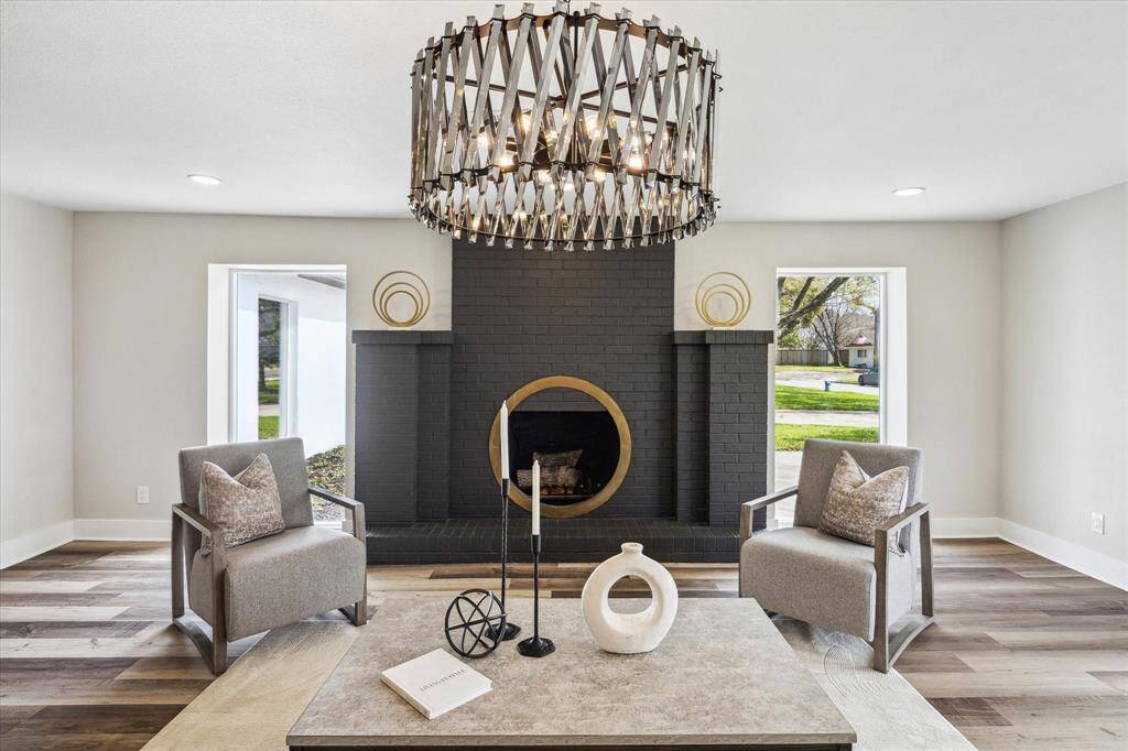 The bold fireplace adds a unique touch to the living room, featuring a sleek black brick surround and a striking circular gold-accented opening. This eye-catching design not only serves as a stunning focal point but also creates a warm and inviting atmosphere, perfect for both gatherings and quiet evenings in.