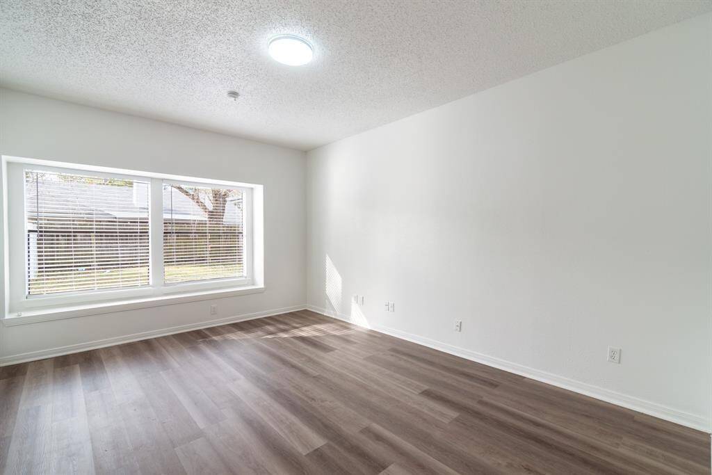 Bright, spacious room with large window, modern wood-style flooring, and neutral walls, providing a blank canvas for personalization. Perfect for a living area or bedroom.