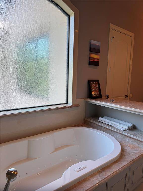 Curved rain glass privacy window lets in light over the Spa tub. A shelf for towels or wine glasses is conveniently located.