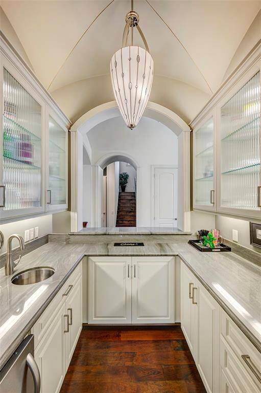 Stunning Wet bar has custom design, ice maker, beverage refrig, lighted rippled glass cabinets and lights underneath. Groin ceiling with Murano like glass chandelier. Lots of cabinets for liquor or other refreshing drinks. Soda anyone?