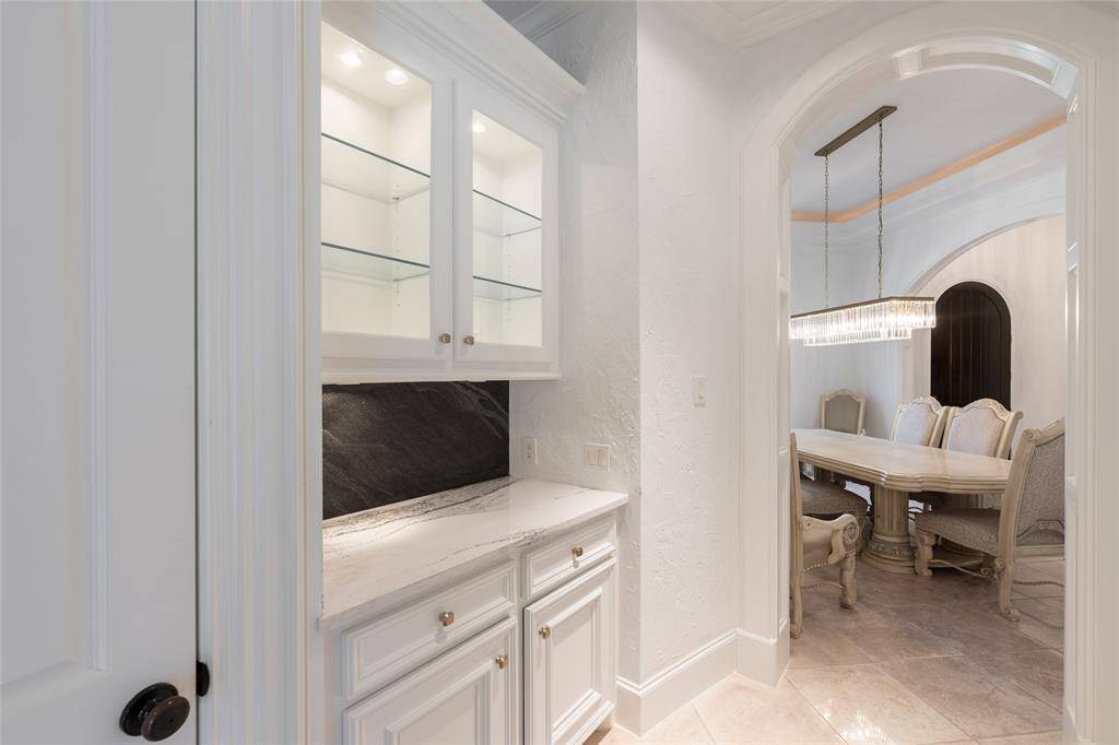 The dining room features a stylish chandelier, framed by an arched doorway.