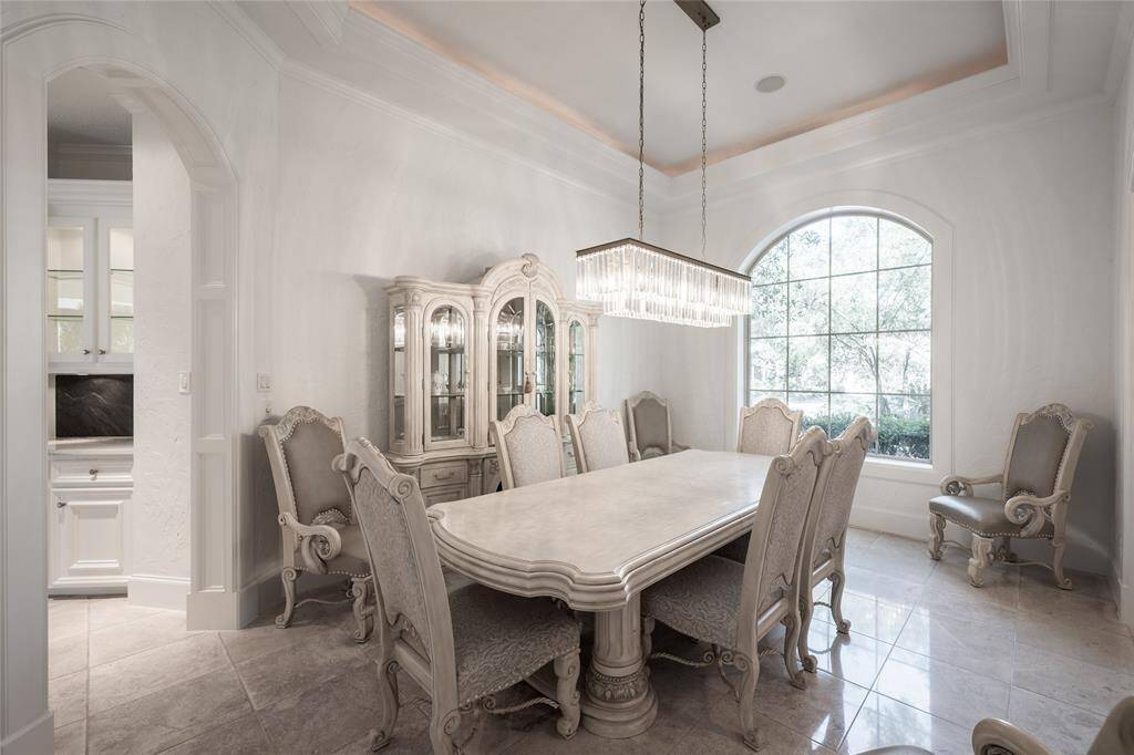 Elegant dining room featuring a crystal chandelier and a bright, arched window that brings in natural light.