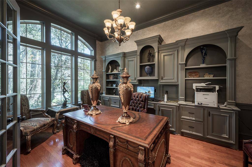 This elegant home office features large arched windows offering plenty of natural light, built-in shelves with decorative moldings