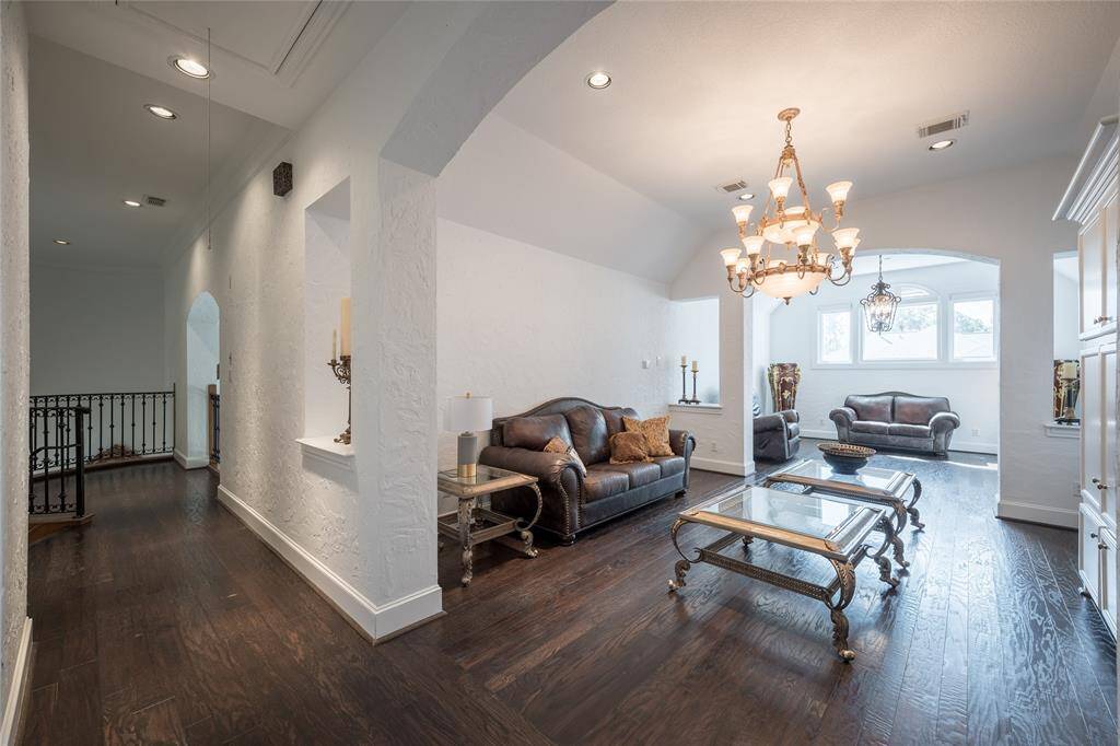 This spacious game room area features elegant wood flooring. The room is well-lit with natural light from large windows, creating a warm and inviting atmosphere.