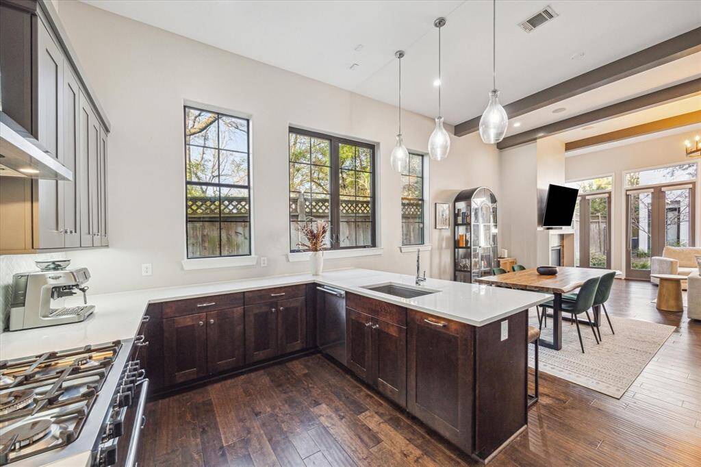Chef-inspired kitchen features quartz countertops, a six-burner gas range, under-cabinet lighting, and a statement stainless steel vent hood. Large island with bar seating offers the perfect setup for casual dining and entertaining.