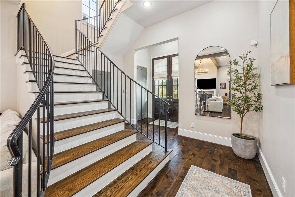Elegant stairwell showcases wood treads, iron balusters, and a gracefully curved railing. Natural light and high ceilings give the entryway a grand and open feel.