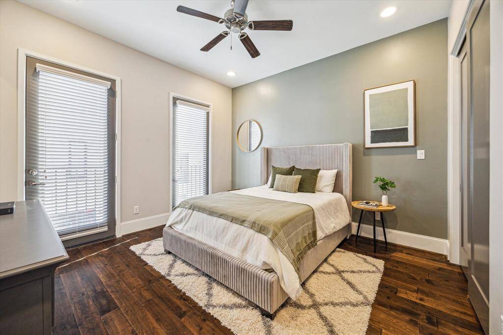 Secondary bedroom is bright and inviting with wood floors, soft accent wall, and private access to a balcony. Ideal for guests or a home office.