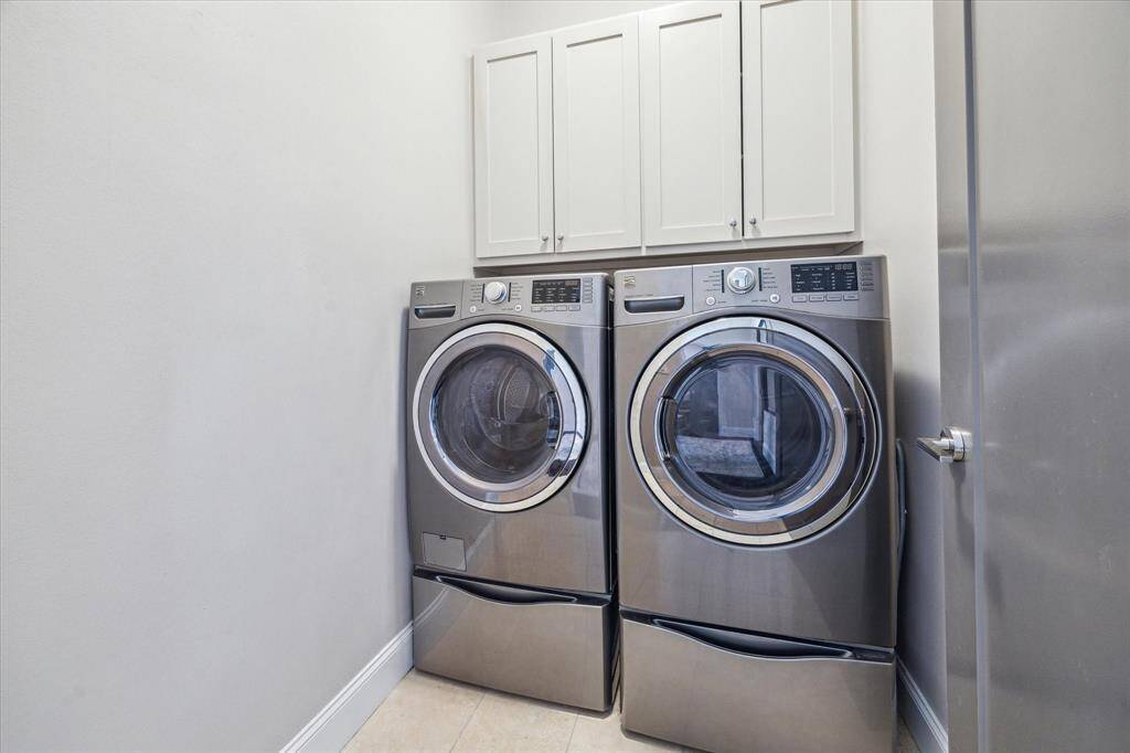 Convenient second floor laundry room includes full-size front-loading washer and dryer with built-in cabinetry for storage.