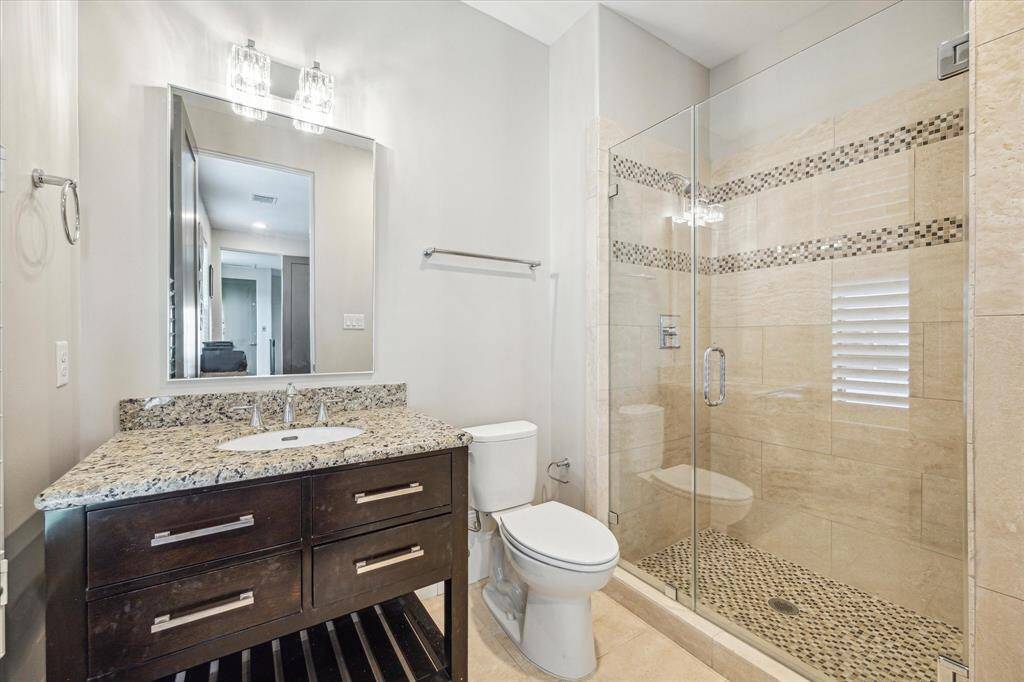 A beautifully appointed third bathroom features a glass-enclosed shower, granite countertops, and mosaic tile accents.