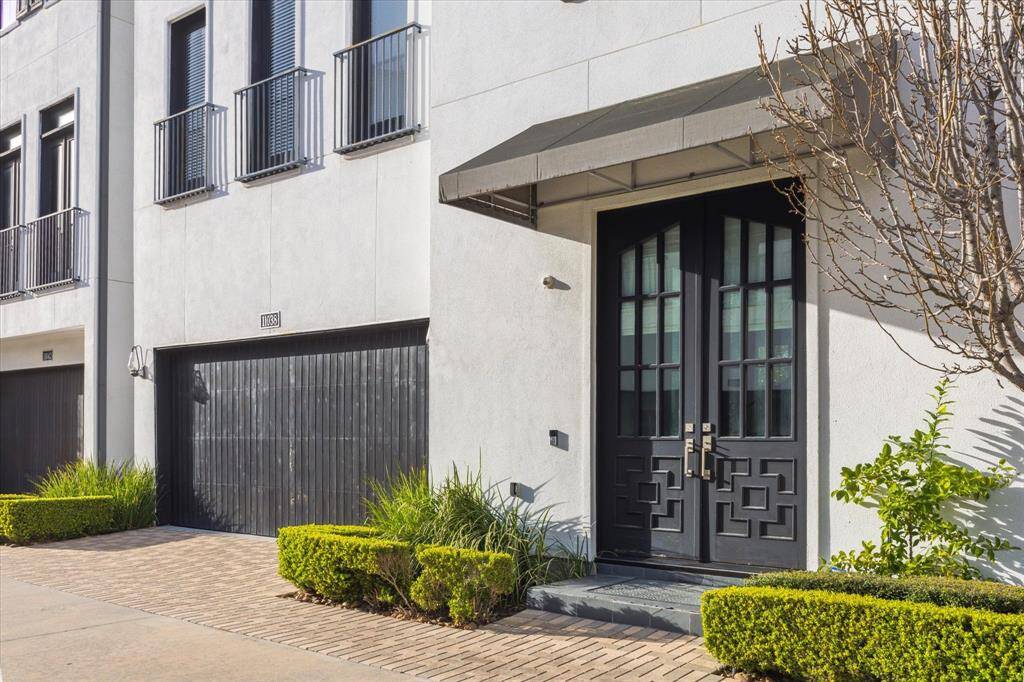 Freshly painted garage door and front doors. Close-up of the elegant front entryway, featuring custom wrought iron double doors and stylish awning. The front landscaping is immaculately maintained for impressive curb appeal