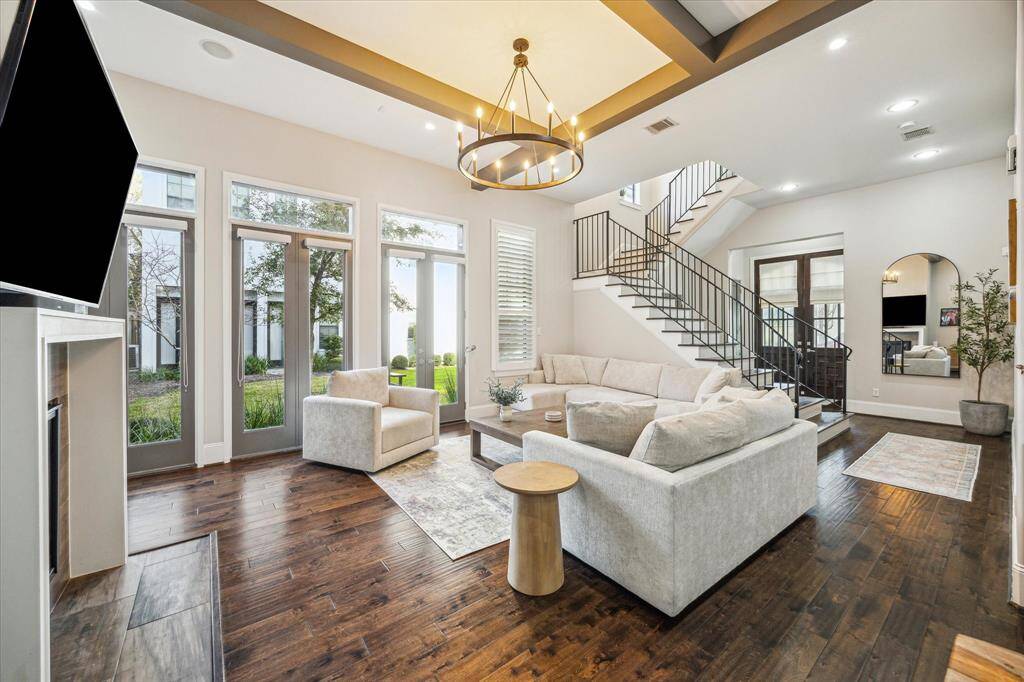 Another angle of the open-concept living room shows seamless indoor-outdoor flow through multiple French doors. Perfect for entertaining or enjoying the community green space.
