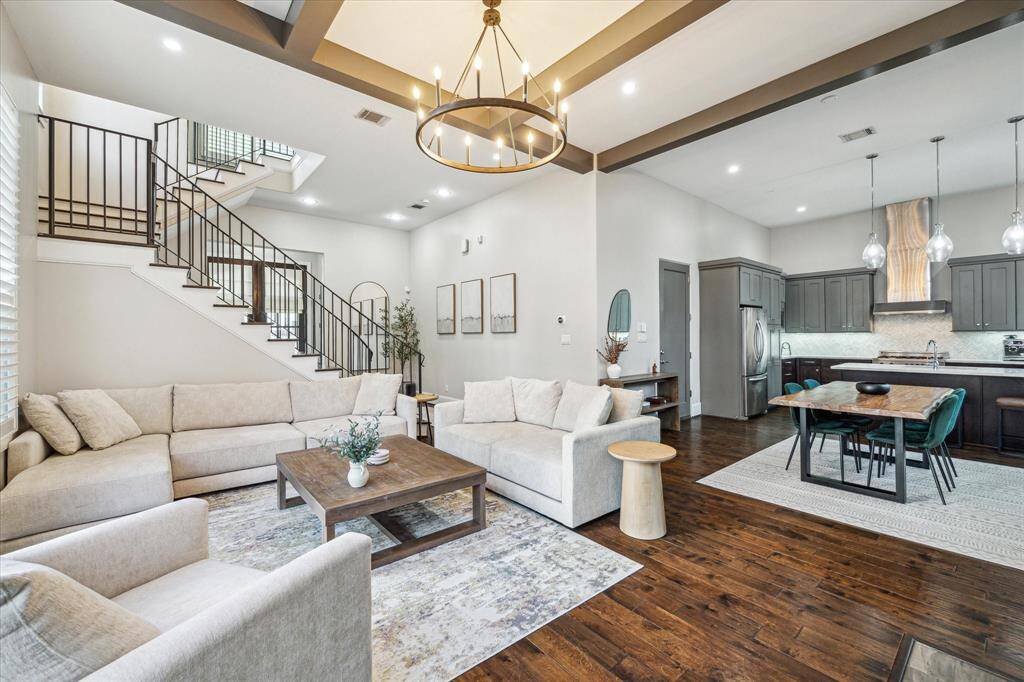 Large, open floor plan connects the living, dining, and kitchen areas under dramatic ceiling beams and designer lighting. A perfect layout for modern living.