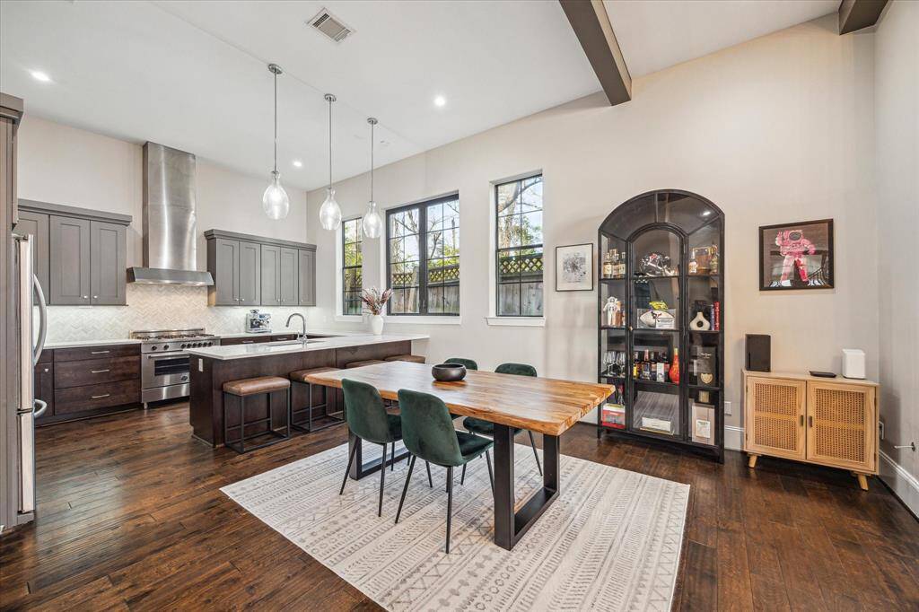 Beautifully designed dining area seamlessly flows into the kitchen, enhanced by natural light from oversized windows. Pendant lighting and a custom live-edge wood table add warmth and character to the space.