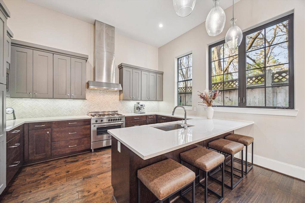 Chef's kitchen with stainless steel appliances, quartz countertops, and custom cabinetry. A large island with bar seating provides the perfect gathering space.