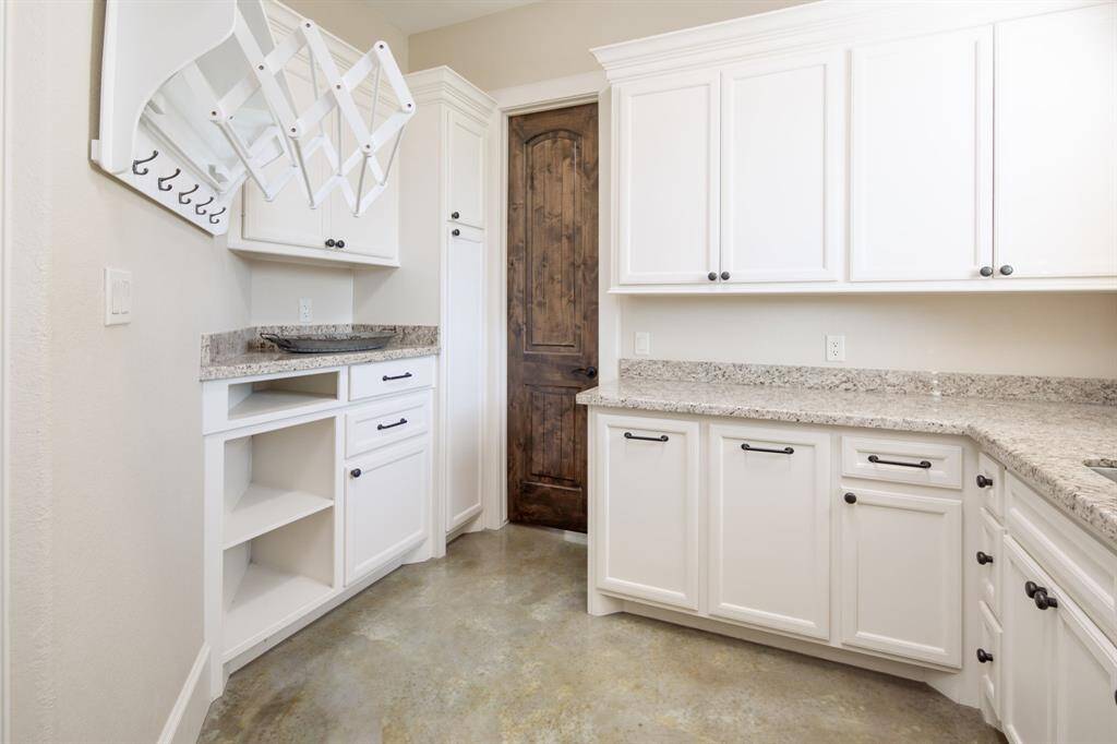 Welcome to the ultimate laundry room! Custom clothes rack, cabinetry with laundry basket pull outs, a custom pedestal for your washer and dryer AND a sink.