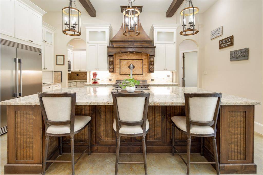 The chef's kitchen is stunning with an oversized island, high ceiling, custom site-built cabinetry and elevated appliances.
