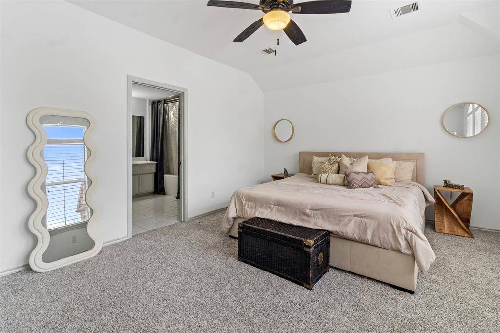Spacious primary bedroom featuring plush carpeting, a generous walk-in closet, and large windows that offer a view of the city. The en-suite bathroom adds another touch of luxury to the space.