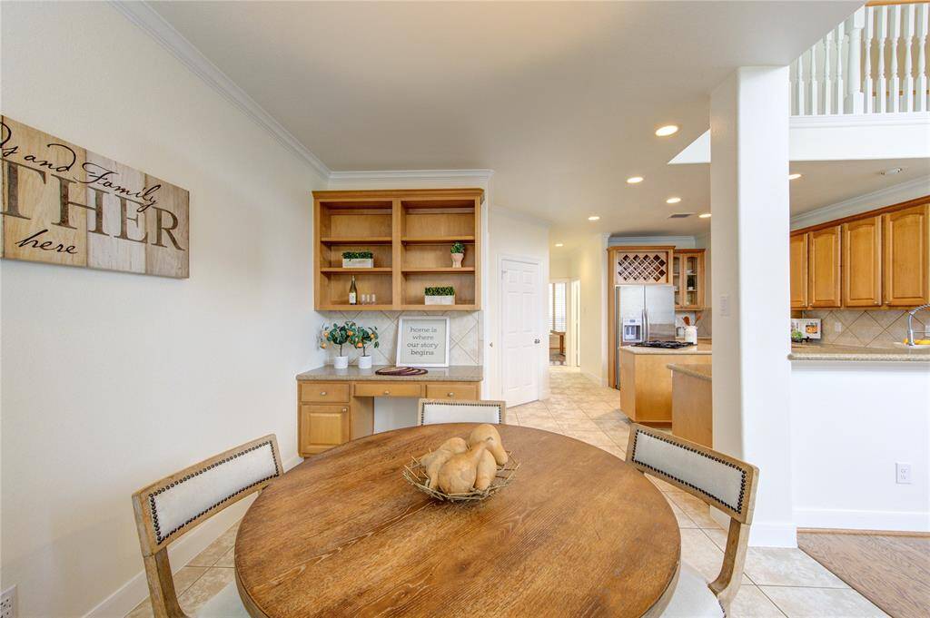 The adjacent breakfast nook is bathed in natural light from large windows with plantation shutters, making it an inviting space to start the day.