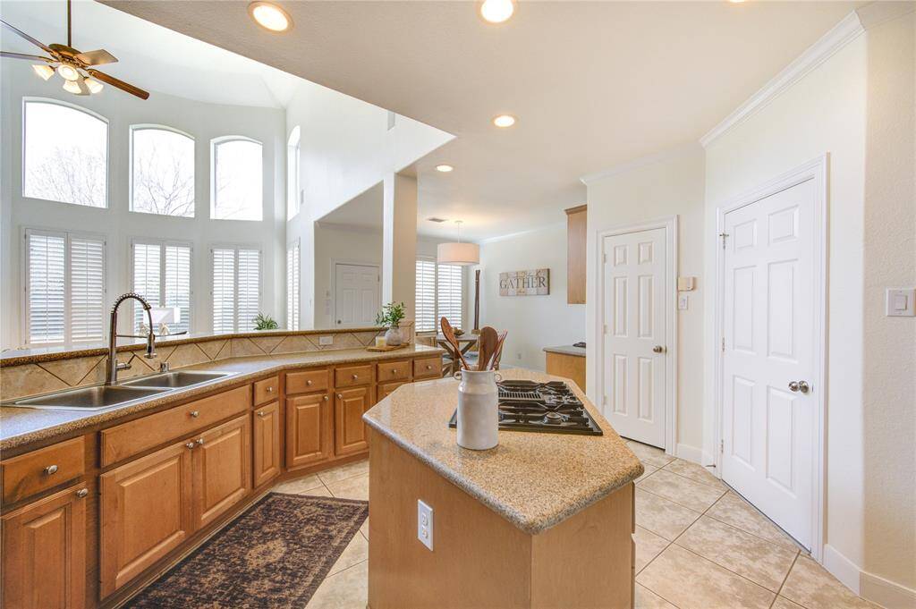 This beautifully maintained chef’s kitchen showcases natural wood cabinetry, offering both warmth and timeless appeal. The granite countertops provide ample workspace, while the gas cooktop and built-in oven ensure effortless meal preparation. The adjacent breakfast nook is bathed in natural light from large windows with plantation shutters, making it an inviting space to start the day.